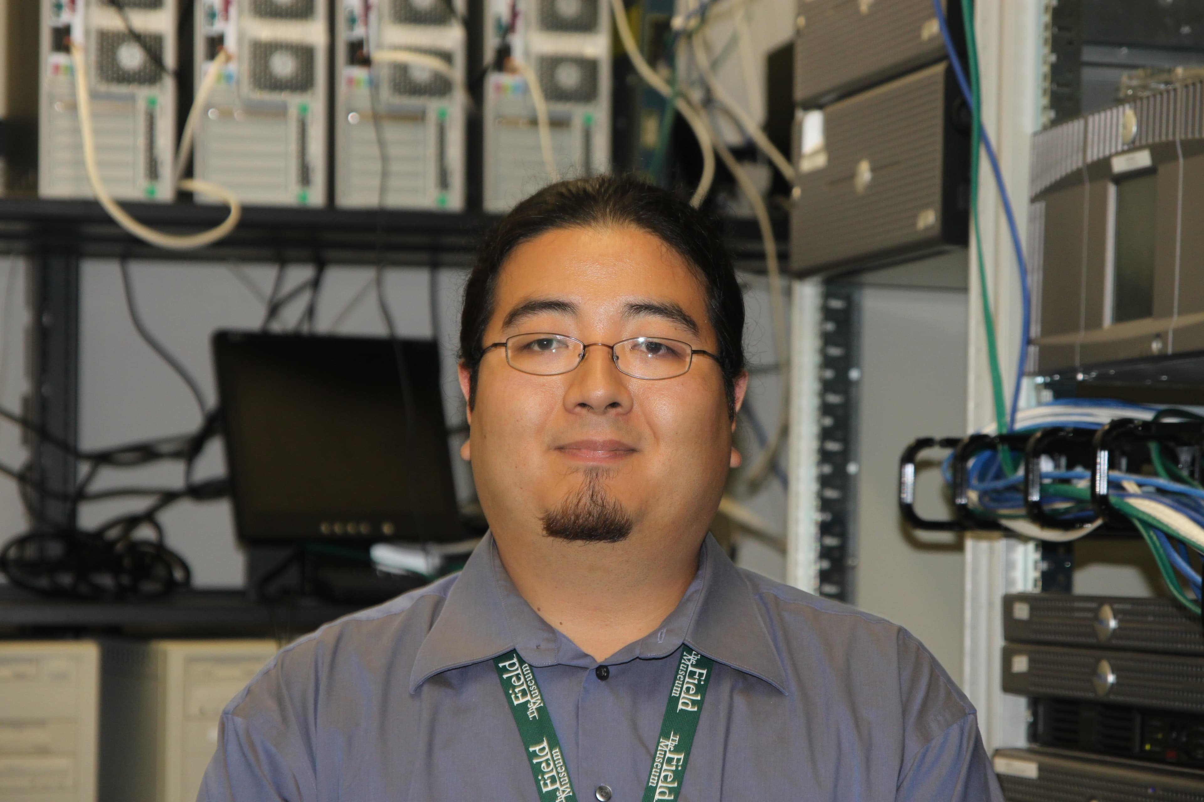 A man wearing glasses stands in front af shelves of computer equipment