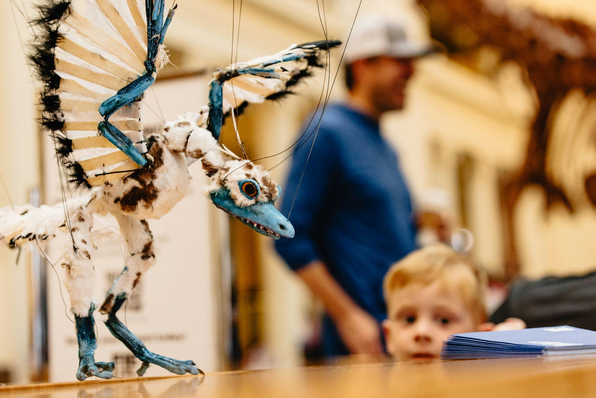 A prehistoric bird puppet, with a childs face blurred in the background