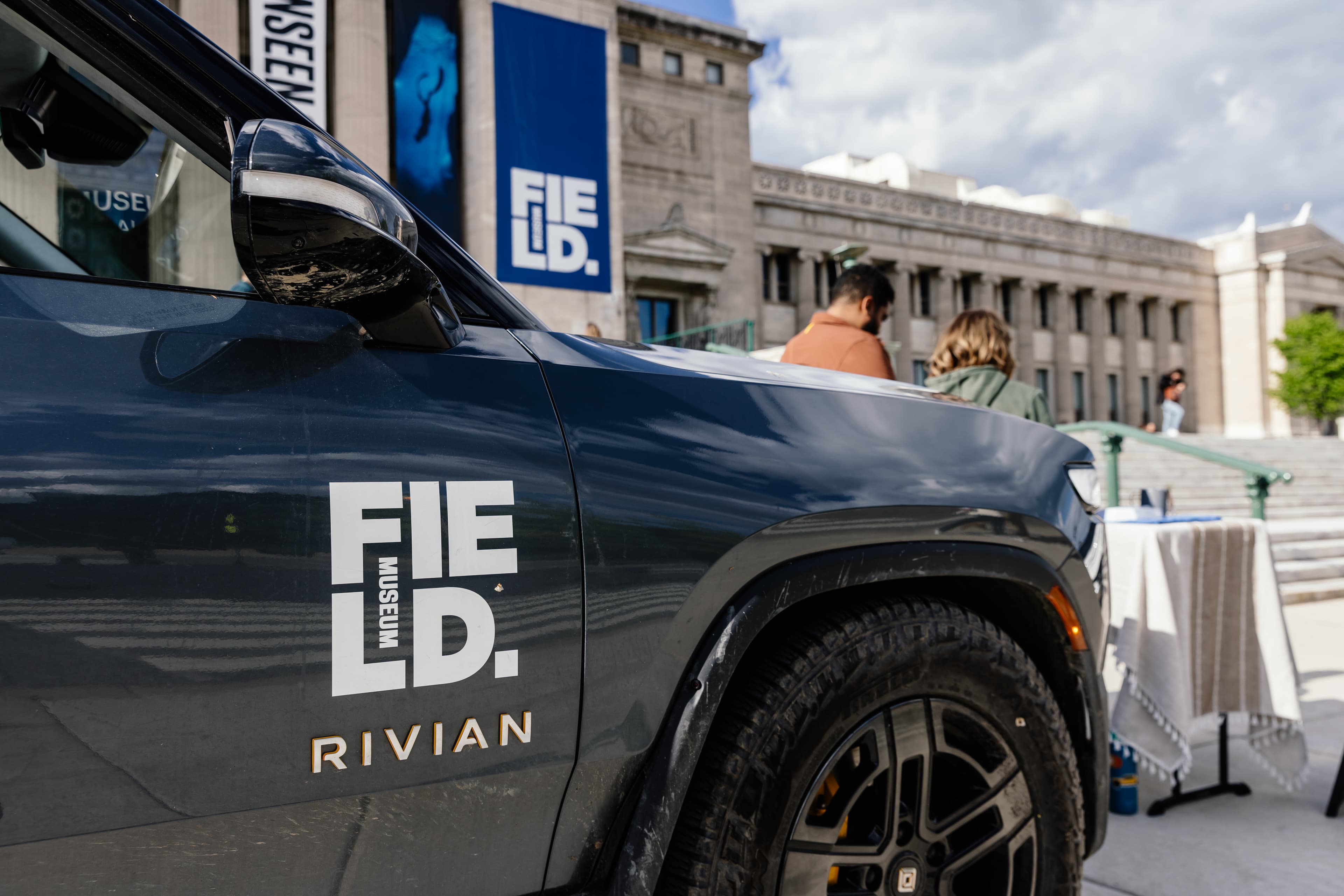 The front corner of a black vehicle with the Field Museum building slighlty blurred in the background.